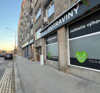 Ulice Krížna v Bratislavě, vedle cesty se nachází potraviny s reklamními nápisy.