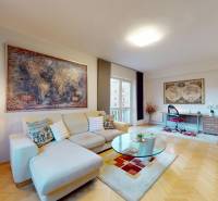 Obývací pokoj dvoupokojového bytu s podlahou s dřevěným dekorem, pohovkou a pracovním stolem.