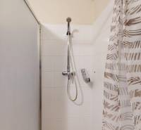 Koupelna v 2-pokojovém bytě s bílými obkladačkami a sprchovým koutem.