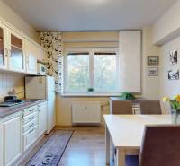 Kuchyně v 2-pokojovém bytě s podlahou s dřevěným dekorem, jídelním stolem a květinami.