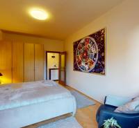 Ložnice v 2pokojovém bytě s velkou postelí, obrazem na stěně a podlahou s dřevěným dekorem.