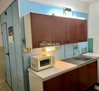 Kuchyně se staršími skříňkami, mikrovlnkou a sporákem ve 4-pokojovém bytě.