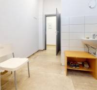 Obchodní prostory s umyvadlem, bílou stěnou a podlahou s dřevěným dekorem.