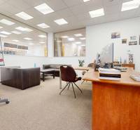 Obchodní prostory s dřevěným stolem, koženými sedačkami a tabulí na konference.