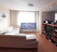 Obývací pokoj s bílou sedačkou a televizorem, podlaha s dřevěným dekorem, 2pokojový byt.