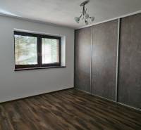 Pokoj v rodinném domě, s podlahou s dřevěným dekorem a velkou vestavěnou skříní.