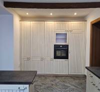 Kuchyně s tmavou pracovní deskou a vestavěnou troubou, podlaha s dřevěným dekorem.