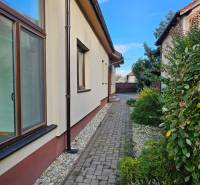 Pohled na boční část rodinného domu v Štúrově ulici ve Vráblech s dlážděným chodníkem.