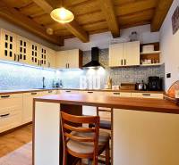 Kuchyně v chatě s dřevěným stropem, podlahou s dřevěným dekorem a modrými obklady.