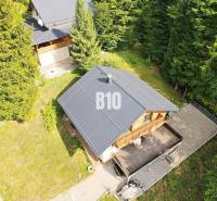 Chata v Terchové obklopená lesem s dřevěnou terasou a přilehlou zahradou.