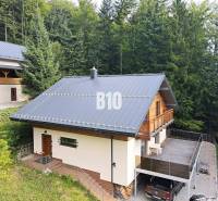 Chata v Terchové obklopená lesy s velkou terasou a parkovacím místem.