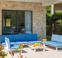 Exteriér vily v Bale s modrým zahradním posezením a kamennou zdí.