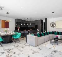 Prostorný obývací pokoj vily s jídelnou, sedačkou a moderní kuchyní.