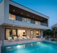 Vila v Balích s bazénem, lehátky a terasou během soumraku.