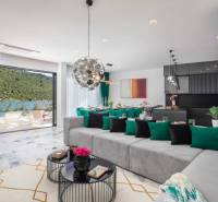 Prostorný obývací pokoj vily s výhledem na bazén a přírodní prostředí.