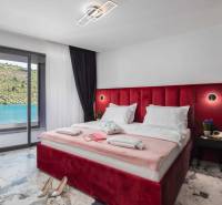 Ložnice ve vile s velkou postelí a výhledem na jezero, podlaha s mramorovým vzorem.