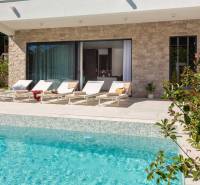 Exteriér vily v Bale s bazénem a lehátky na terase.