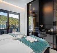 Ložnice ve vile s terasou a výhledem na přírodu a jezero.