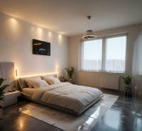 Ložnice s podlahou s dřevěným dekorem, velká postel, rostliny a zapuštěné osvětlení.