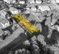 Pozemek k bydlení v Turzovce, obklopený domy, s travnatým porostem a stromy.