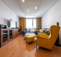 Obývací pokoj ve 4-pokojovém bytě s podlahou s dřevěným dekorem a žlutými křesly.