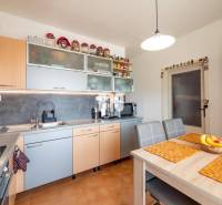 Kuchyně ve 4-pokojovém bytě s počítačem a kuchyňskou linkou v dřevěném dekoru.