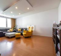 Obývací pokoj ve 4pokojovém bytě s podlahou s dřevěným dekorem a pohodlným nábytkem.