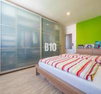 Ložnice ve 4pokojovém bytě s podlahou s dřevěným dekorem a prostornou skříní.