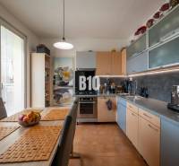 Kuchyně ve 4-pokojovém bytě s jídelním stolem a vestavěnými spotřebiči.