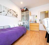 Pokoj ve 4pokojovém bytě s jednolůžkem, skříní a podlahou s dřevěným dekorem.