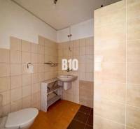 Koupelna v rodinném domě s béžovým obkladem a bílými sanitárními zařízeními.