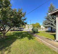 Zahrada u rodinného domu v Ondrejovcích s trávníkem, stromy a keři.