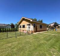 Rodinný dům v Nových Sadech obklopený prostornou, zelenou zahradou a plotem.