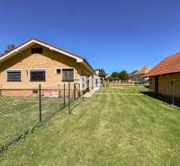 Rodinný dům v Nových Sadech se dvěma budovami a travnatým pozemkem, obklopený plotem.