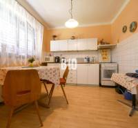 Kuchyně v rodinném domě s jídelním stolem, linkou a spotřebiči.