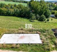 Pozemek k bydlení v Čeľadicích, zelená krajina s betonovým základem a automobilem.