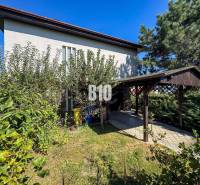 Rodinný dům na Kamennej ulici v Nitře obklopený zelení a přístřeškem pro auto.