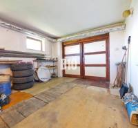 Garáž v rodinném domě s dřevěnými dveřmi a podlahou podobnou dřevěnému dekoru.