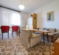 Obývací pokoj v rodinném domě s kobercem a červenými židlemi.