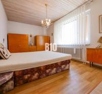 Ložnice s podlahou s dřevěným dekorem v rodinném domě, s nábytkem a lustry.