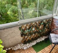 Zasklený balkon s dřevěným dekorem a rostlinami v 2-pokojovém bytě.