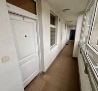 Chodba v 2-pokojovém bytě s bílými dveřmi a dlažbou.