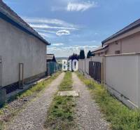 Úzká cesta mezi domy v lokalitě Pozemky - bydlení, Nitra, vedoucí k panoramatu krajiny.