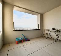 Balkon s výhledem na město, s hračkami a nábytkem v 2-pokojovém bytě.