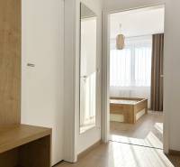 Chodba v 2-pokojovém bytě s podlahou s dřevěným dekorem a zrcadlem na stěně.