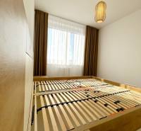 Ložnice s postelí a lampou v dvoupokojovém bytě s podlahou s dřevěným dekorem.