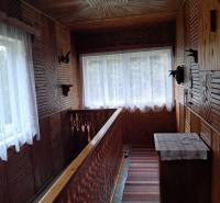 Dřevěný interiér rodinného domu s dekorativním zábradlím a koberci na chodbě.