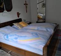 Ložnice v rodinném domě s dřevěným dekorem, velkým zrcadlem a nástěnnými dekoracemi.