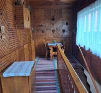 Interiér rodinného domu s podlahou s dřevěným dekorem a tradičními nástěnnými dekoracemi.