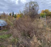 Pozemek na bydlení v Tvrdošovcích s opuštěným autem a zarostlým terénem.